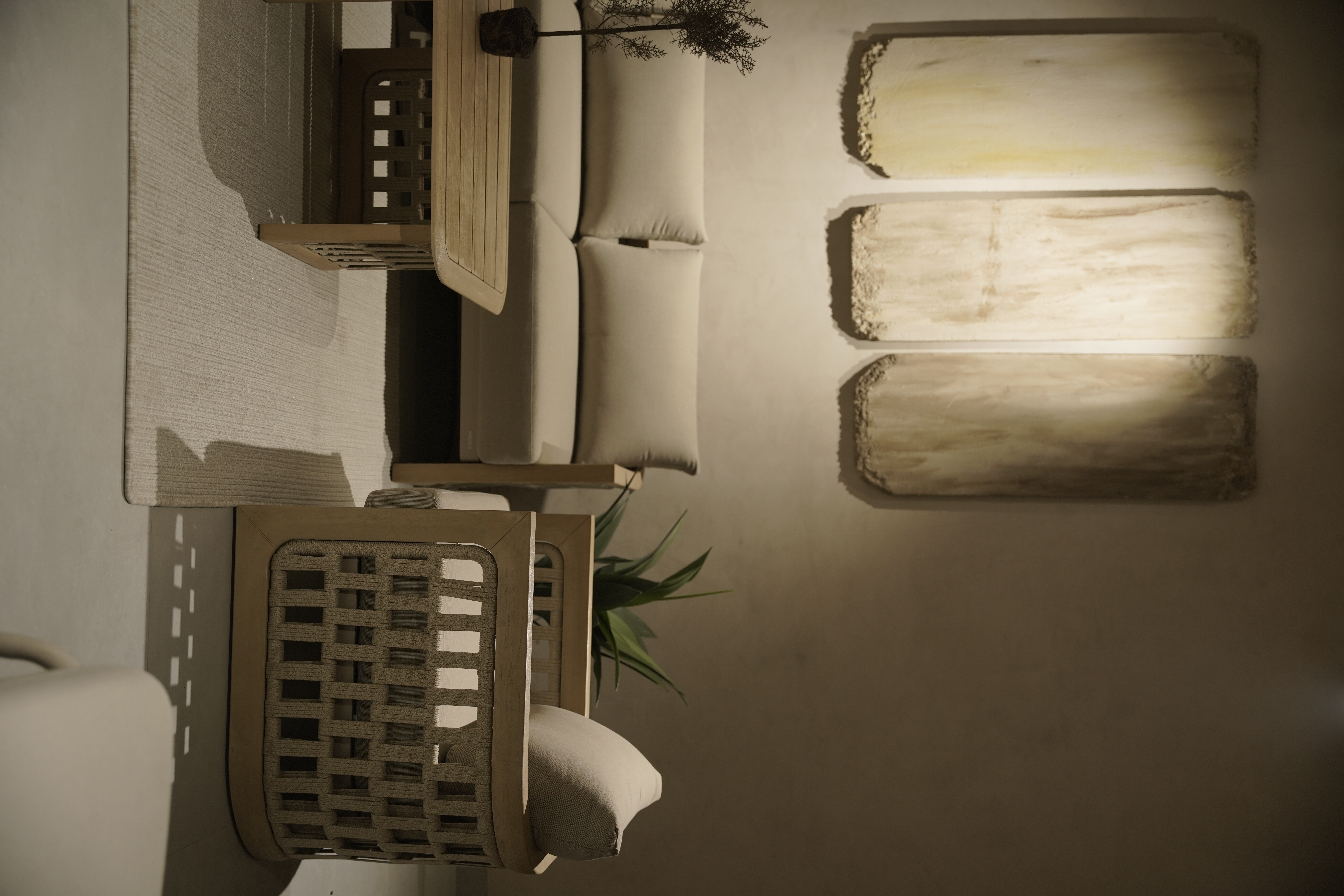 Luxury minimalist living room interior by Shruti Chadha with neutral sofa, handcrafted wooden chairs, organic textures, and warm lighting creating a serene residential space in Delhi.